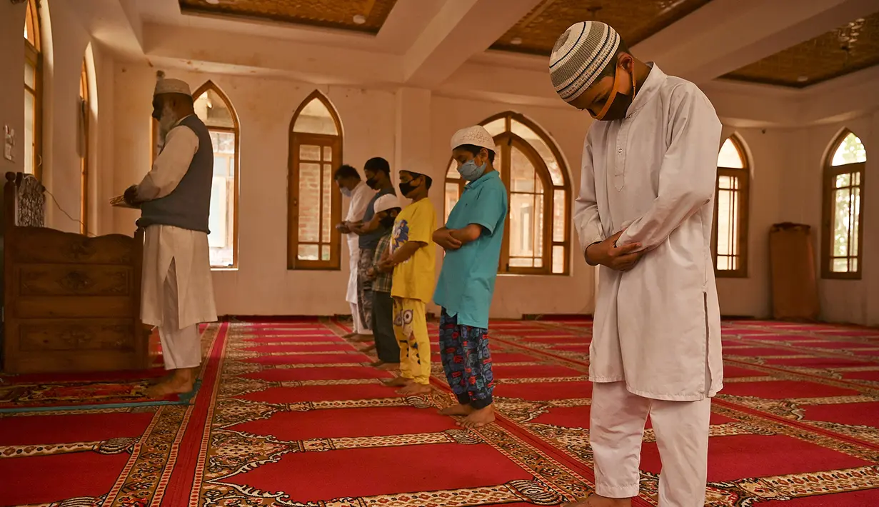 Anak-anak yatim Muslim mengenakan masker melaksanakan salat sambil menjaga jarak sosial di dalam pusat panti asuhan selama bulan suci Ramadan di Srinagar (11/5/2020). (AFP/Tauseff Mustafa)