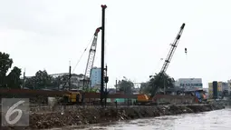 Alat berat dikerahkan untuk memasang pasak di bantaran Kali Ciliwung, Bukit Duri, Jakarta (1/11). Pemasangan tiang pancang untuk sheet pile di kali tersebut ditargetkan hingga 2000 meter dan selesai akhir Desember 2016. (Liputan6.com/Gempur M Surya)