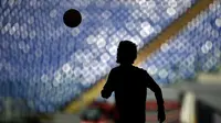 Siluet seorang pemain saat melakukan pemanasan jelang pertandingan antara AS Roma melawan Lazio dalam lanjutan Serie A di Stadion Olimpico, Roma, Minggu (8/11/2015) malam WIB. (AFP Photo/Filippo Monteforte)