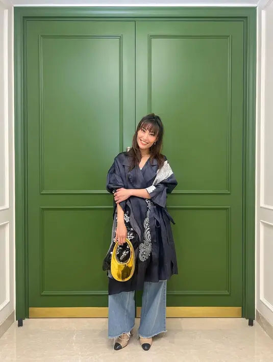 Padu padan outfit menarik ala Ayu Dewi. Atasan biru navy bersiluet kimono oversized, dipadunya dengan wide-leg jeans, dan handbag berwarna kontras, namun serasi. [Foto: Instagram/mrsayudewi]
