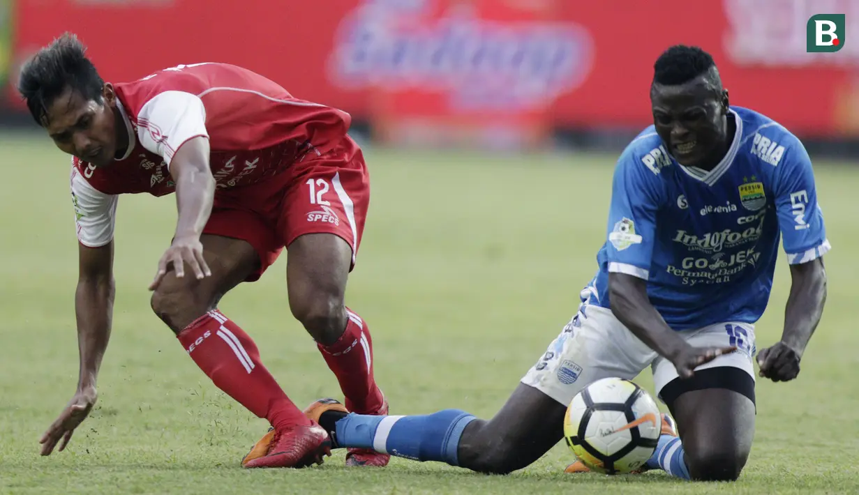 Striker Persib Bandung, Ezechiel N'Douassel, terjatuh saat berebut bola dengan gelandang Arema FC, Hendro Siswanto, pada laga Liga 1 di Stadion GBLA, Jawa Barat, Kamis (13/9/2018). Persib menang 2-0 atas Arema FC. (Bola.com/M Iqbal Ichsan)