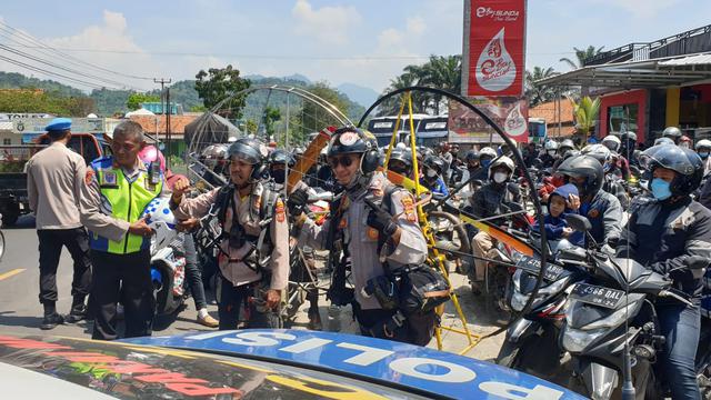Dua petugas polres Garut, Jawa Barat nampak ceria di depan pemudik via Limbangan-Malangbing sesaat menerbangkan paramotor di sekitar arus balik jalur nasional itu. (Liputan6.com/Jayadi Supriadin)