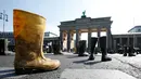 Sepatu boots wellington diletakkan di depan gerbang Brandenburg, Berlin saat aksi protes oleh peternak sapi perah di Jerman, Senin (30/5). Mereka menuntut harga produk susu yang lebih adil bagi para peternak. (REUTERS/Fabrizio Bensch)