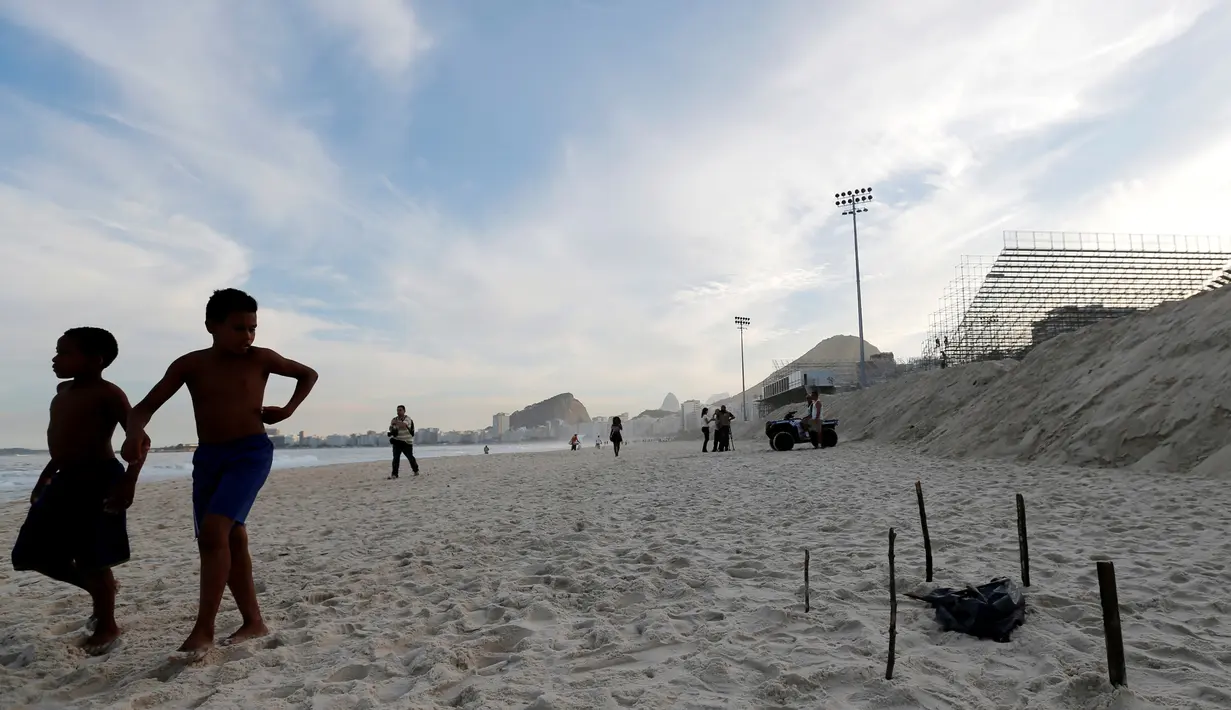 Anak-anak berjalan di dekat bagian tubuh yang terpotong di Pantai Copacabana, Rio de Janeiro, Brasil (29/6). Potongan tubuh yang menggegerkan warga lokal dan turis tersebut  ditemukan di dekat arena voli pantai Olimpiade 2016. (REUTERS/Sergio Moraes)