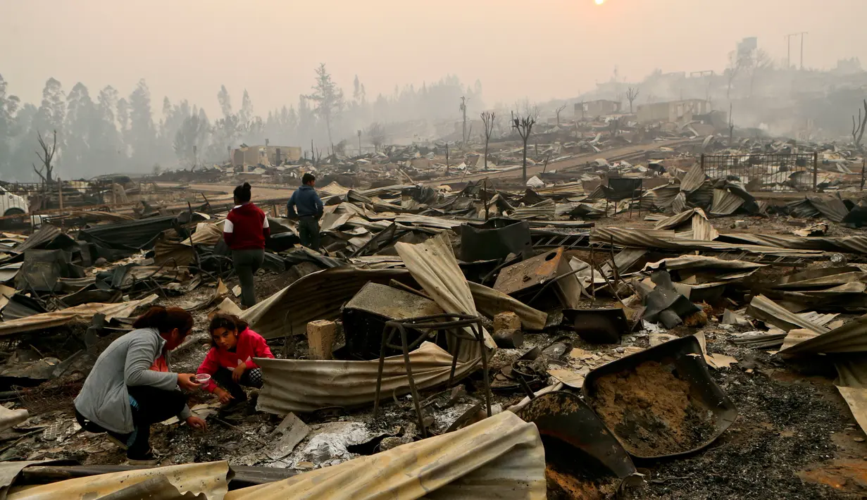 Warga mencari barang miliknya usai kebakaran hebat melanda tempat tinggalnya di Santa Olga, Chile, (26/1). Chile dilanda kebakaran hutan terbesar yang menghanguskan ratusan rumah, sejumlah fasilitas umum, dan juga sekolah. (Javier Torres/Aton via AP)