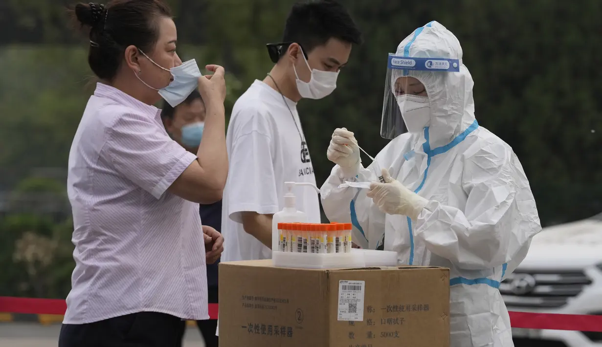 <p>Seorang pekerja medis mengumpulkan sampel swab dari seorang warga selama pengujian massal untuk COVID-19 di distrik Chaoyang, Bejing, Senin (25/4/2022). Ibu kota China, Beijing, mulai menguji jutaan penduduk dan menutup kawasan perumahan dan bisnis pada Senin di tengah wabah baru COVID-19. (AP Photo/Ng Han Guan)</p>