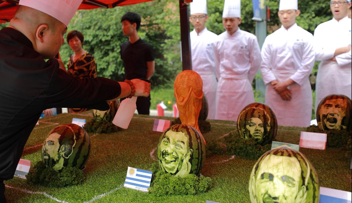 Seorang guru sekolah menengah mengukir semangka dengan wajah para pemain sepak bola ternama seperti Lionel Messi dan Neymar di Shenyang, Provinsi Liaoning, China, Selas (10/7). (AFP)