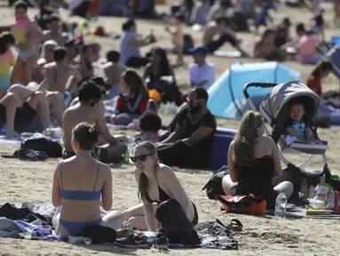 Orang-orang menikmati cuaca hangat di Ruislip Lido di London, Selasa (30/3/2021).  Suhu di beberapa bagian Inggris diperkirakan akan lebih hangat secara signifikan minggu ini karena keluarga dan teman berkumpul kembali dan kegiatan olahraga luar ruangan diizinkan untuk dilanjutkan di Inggris. (AP Ph