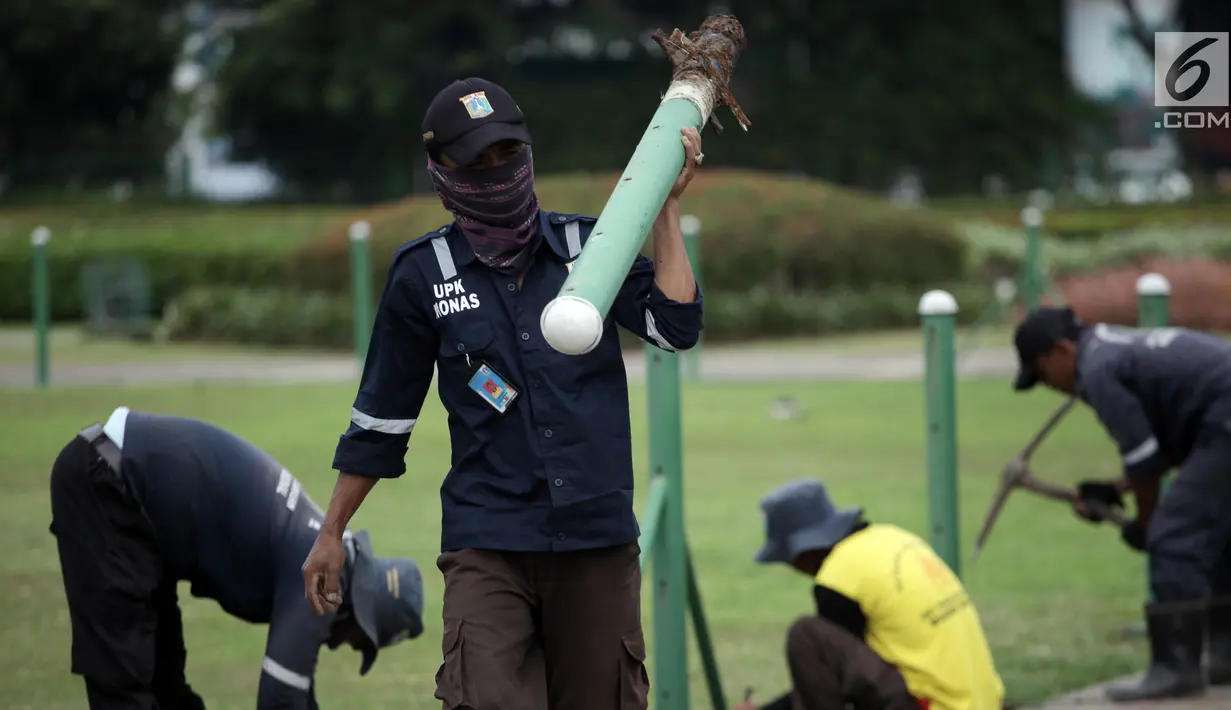 Petugas UPK Monas membawa pagar pembatas rumput yang sudah dicopot di kawasan Monas, Jakarta, Jumat (11/1). Pencopotan ini adalah wujud dari keinginan Wagub DKI Sandiaga Uno agar warga leluasa menikmati Monas sebagai taman. (Liputan6.com/Arya Manggala)