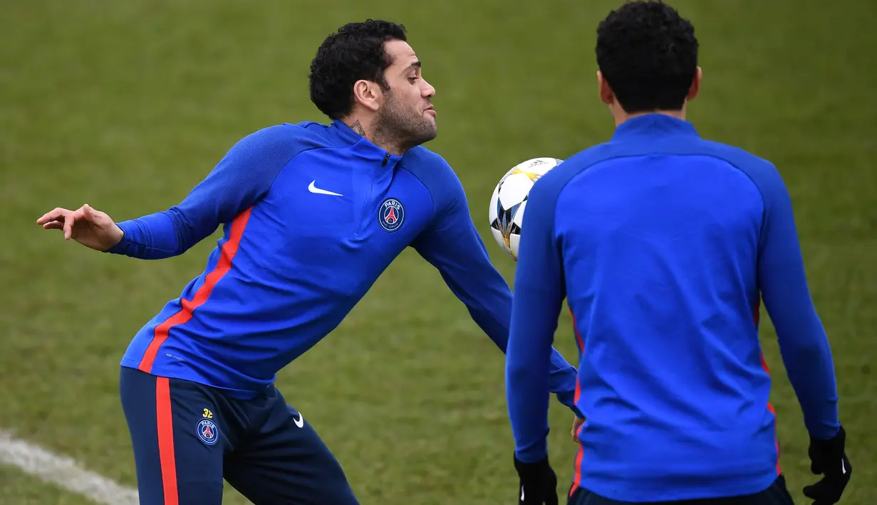 Gaya pemain PSG, Daniel Alves (kiri) menahan bola saat sesi latihan sebelum leg kedua Liga Champions melawan Real Madrid di Ooredoo training center, Saint-Germain-en-Laye,Paris, (5/3/2018). Leg pertama PSG kalah 1-3. (AFP/Franck Fife)