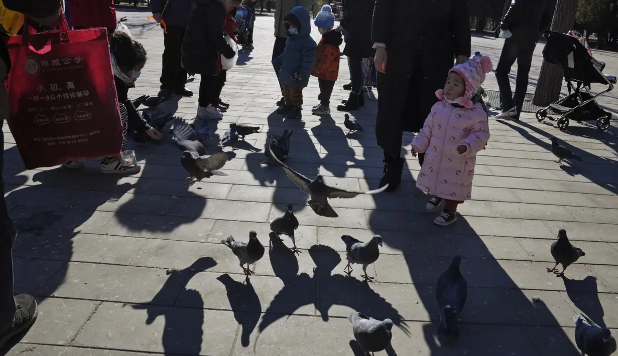 Seorang anak melihat ke dekat merpati di sebuah taman di Beijing, China (13/1/2022). Partai Komunis yang berkuasa khawatir fakta ini bisa menghalangi ambisi mereka untuk meningkatkan kekayaan nasional dan pengaruh global. (