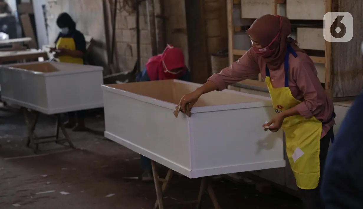 Pekerja menyelesaikan pembuatan peti jenazah COVID-19 di Batu Ceper, Kota Tangerang, Banten, Selasa (29/6/2021). Produksi peti jenazah COVID-19 di tempat tersebut meningkat hingga dua kali lipat dari 500 buah menjadi 1.000 buah per minggunya akibat tingginya permintaan. (Liputan6.com/Angga Yuniar)