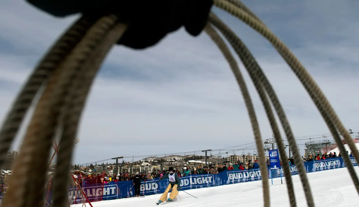 Seorang koboi rodeo meluncur di atas papan ski selama turnamen Cowboy Downhill ke-46 di Steamboat Springs, Colorado, 20 Januari 2020. Para koboi yang biasa menunggangi kuda atau banteng ini ditantang untuk meluncur menggunakan papan ski dan snowboard. (Jason Connolly/AFP)