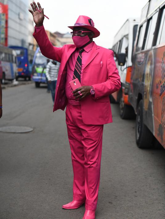 Fashionista Kenya, James Mwangi Maina berjalan-jalan sambil memamerkan setelan jasnya yang senada dengan pakaian dan aksesorisnya, termasuk masker di Nairobi, 5 Agustus 2020. Mwangi mengklaim dirinya memiliki penampilan terbaik dan paling stylish di Afrika. (Simon MAINA/AFP)
