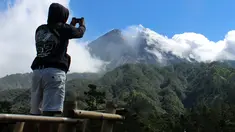 Seorang pria mengambil gambar Gunung Merapi di Cangkringan, Indonesia, Selasa, (22/5). Pihak berwenang meningkatkan kewaspadaan terhadap Gunung Merapi yang bergejolak di pulau Jawa. (AP Photo/A.K. Hendratmo)