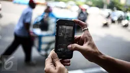Karakter Pokemon terlihat di dekat pedagang keliling pada layar smartphone pemain augmented reality game Pokemon Go di Jakarta, Kamis (14/7). Pokemon Go sedang di puncak ketenaran meski baru diluncurkan di beberapa negara. (Liputan6.com/Faizal Fanani)