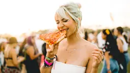 Pengunjung wanita menikmati pizza selama Coachella Music & Arts Festival 2019 di Indio, California (15/4). Festival Coachella ini sudah ada sejak tahun 1999. (AFP Photo/Matt Winkelmeyer)