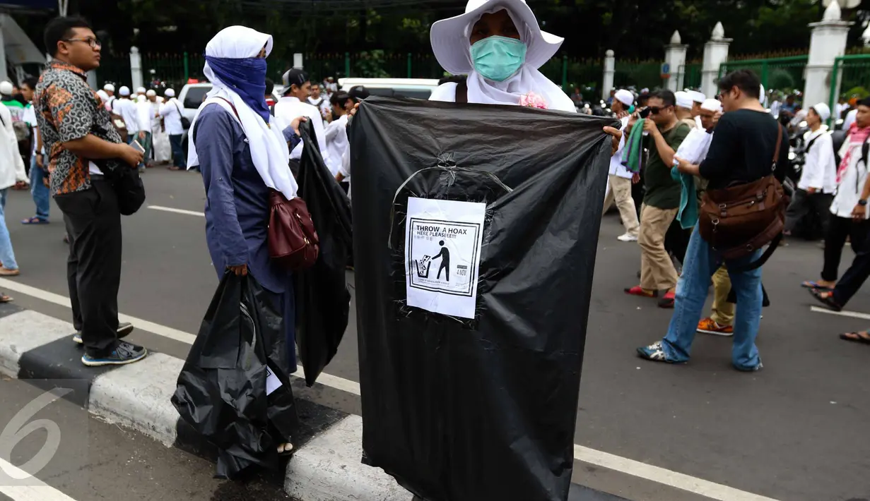 Relawan membawa kantong plastik bertuliskan "Throw A HOAX Here Please" di tengah aksi damai 4 November di Jakarta, Jumat (4/11). Mereka mengumpulkan sampah berupa bekas botol minuman dan bungkus nasi yang dibuang anggota ormas (Liputan6.com/Faizal Fanani)