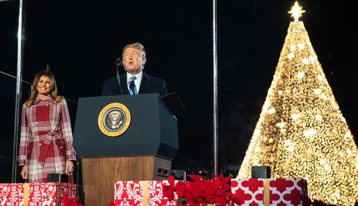 Presiden AS, Donald Trump didampingi ibu negara Melania Trump memberikan sambutan saat upacara penerangan Pohon Natal Nasional di taman sebelah selatan Gedung Putih, Kamis (5/12/2019). Pohon Natal Nasional tahun ini adalah cemara biru segar dari Colorado. (AP/Manuel Balce Ceneta)
