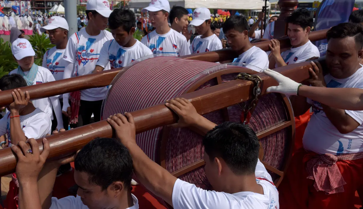 Warga Kamboja membentangkan syal krama untuk memecahkan rekor Guinness sebagai syal tenun terpanjang dunia di Phnom Penh, Minggu (1/7). Syal dengan panjang 1.149,8 meter dan lebar 88 cm tersebut dibentangkan di luar Istana Kerajaan. (AFP/TANG CHHIN Sothy)