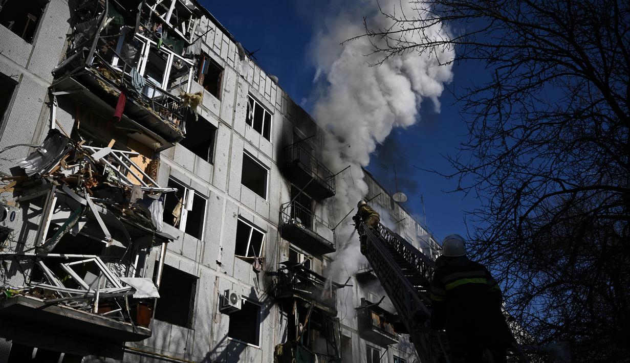 Petugas berusaha memadamkan kebakaran pada sebuah gedung setelah pemboman di Kota Chuguiv, Ukraina timur, 24 Februari 2022. Angkatan bersenjata Rusia mencoba menyerang Ukraina dari beberapa arah, menggunakan sistem roket dan helikopter untuk menyerang posisi Ukraina di selatan. (Aris Messinis/AFP)
