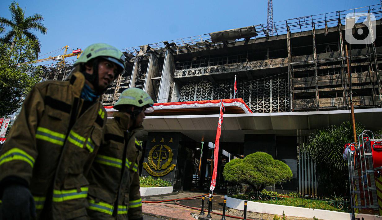 Petugas pemadam kebakaran melintas di depan gedung utama Kejaksaan Agung yang terbakar di Jakarta, Minggu (23/8/2020). Kebakaran yang berawal sejak Sabtu (22/8) malam itu, baru bisa dikuasai pagi ini, Minggu (23/8). (Liputan6.com/Faizal Fanani)