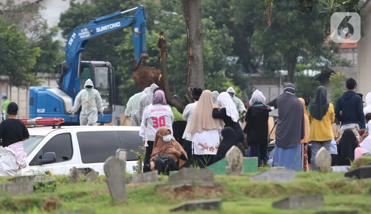 Keluarga dan kerabat menyaksikan pemakaman jenazah dengan protokol COVID-19 dari luar area di TPU Srengseng Sawah, Jakarta, Kamis (21/1/2021). Sebagian lahan TPU Srengseng Sawah yang dijadikan lokasi pemakaman jenazah Covid-19 kini hanya tersisa 79 petak makam. (Liputan6.com/Helmi Fithriansyah)