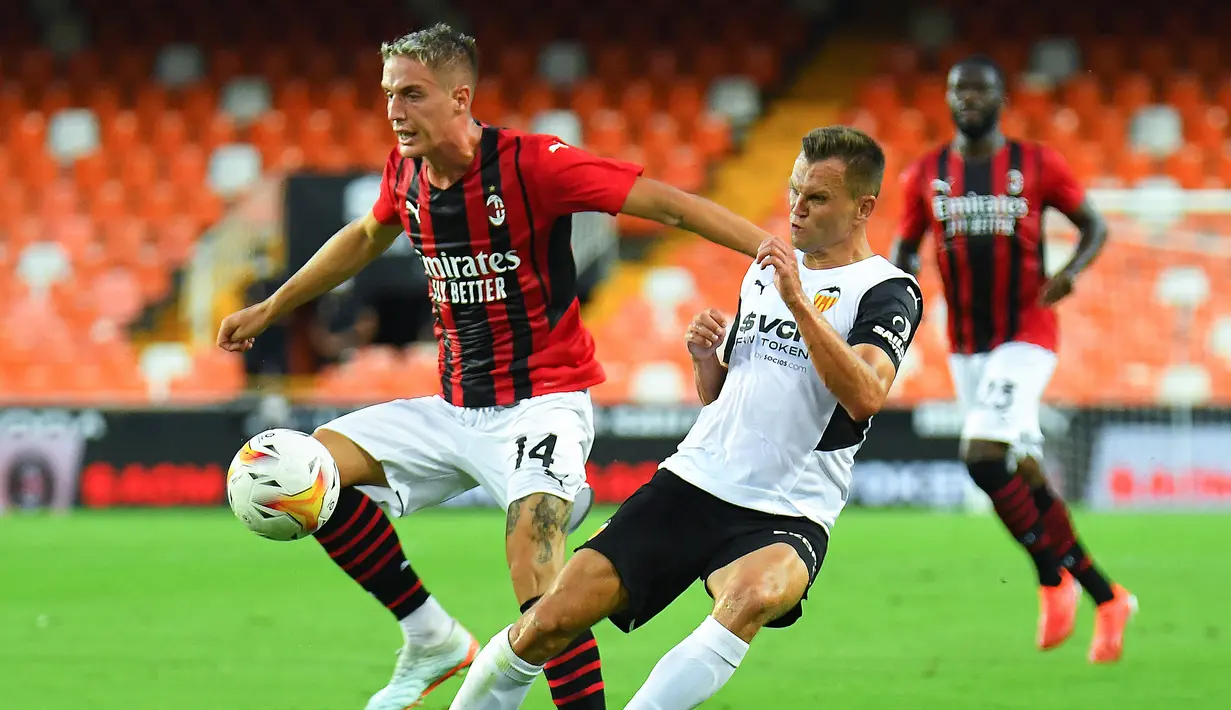 Bek AC Milan, Andrea Conti mengontrol bola dari kawalan gelandang Valencia, Denis Cheryshev selama pertandingan persahabatan di Stadion Mestalla di Valencia (4/8/2021). Bermain imbang 0-0 di waktu normal, AC Milan kalah atas Valencia lewat adu penalti 5-3. (AFP/Jose Jordan)