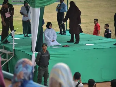 Seorang wanita dicambuk setelah ketahuan melakukan hubungan seks pranikah di sebuah stadion di Lhokseumawe di provinsi Aceh (31/7/2019). Dua pria dan seorang wanita dicambuk secara terbuka sebanyak 100 kali karena melanggar hukum Islam di daerah tersebut. (AFP Photo/Rahmad Mirza)