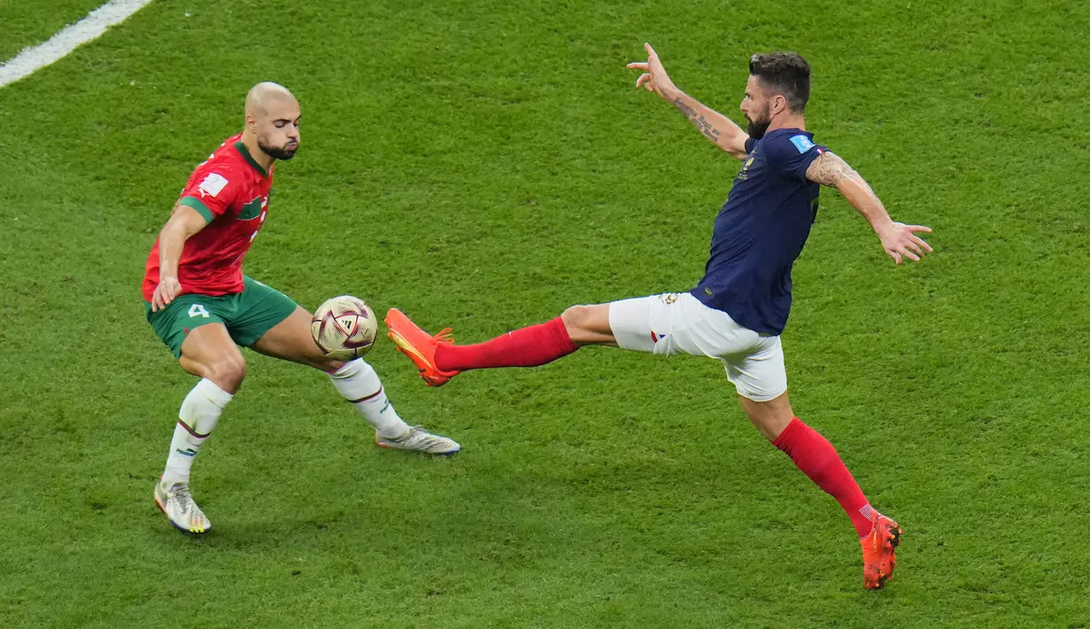 Gelandang Maroko, Sofyan Amrabat berebut bola dengan penyerang Prancis, Olivier Giroud pada pertandingan semifinal Piala Dunia 2022 di Stadion Al Bayt di Al Khor, Qatar, Kamis (15/12/2022).  Prancis menang atas Maroko dengan skor 2-0. (AP Photo/Hassan Ammar)