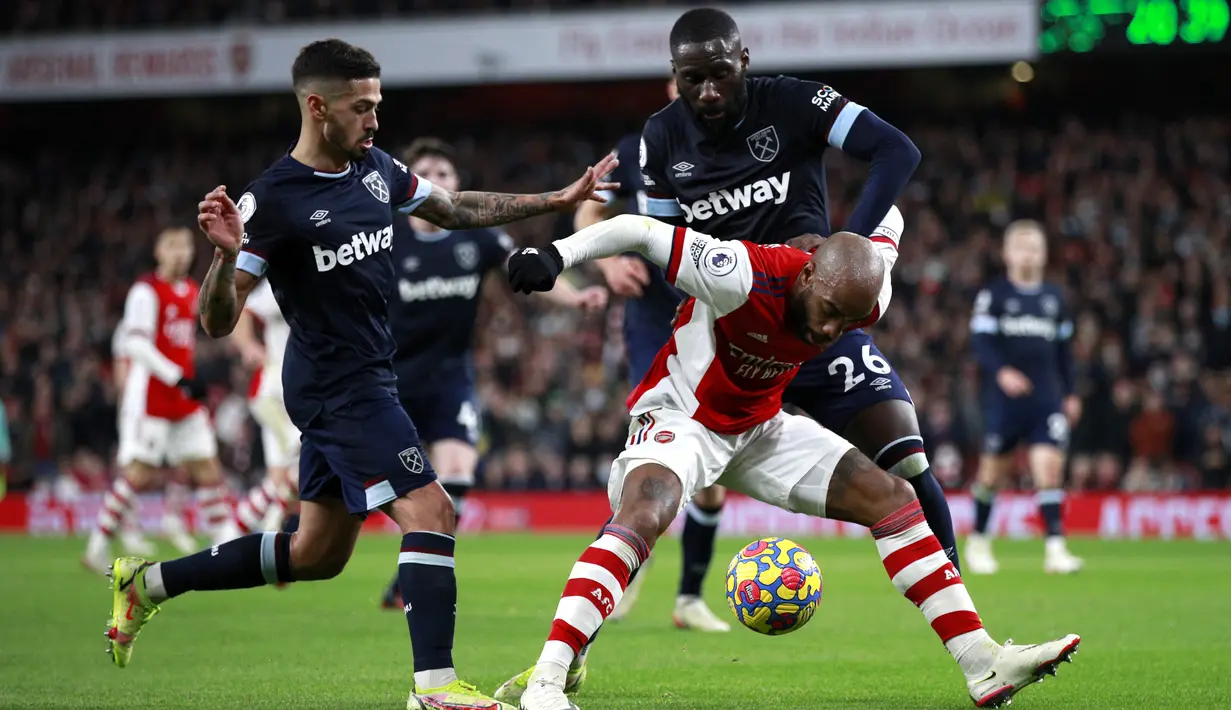 Penyerang Arsenal Alexandre Lacazette berebut bola dengan pemain West Ham United Manuel Lanzini dan pArthur Masuaku dalam laga pekan 17 Liga Inggris di Emirates Stadium, Kamis dini hari WIB (16/12/2021). Arsenal sukses kalahkan tamunya West Ham dengan skor 2-0. (AP Photo/Ian Walton)