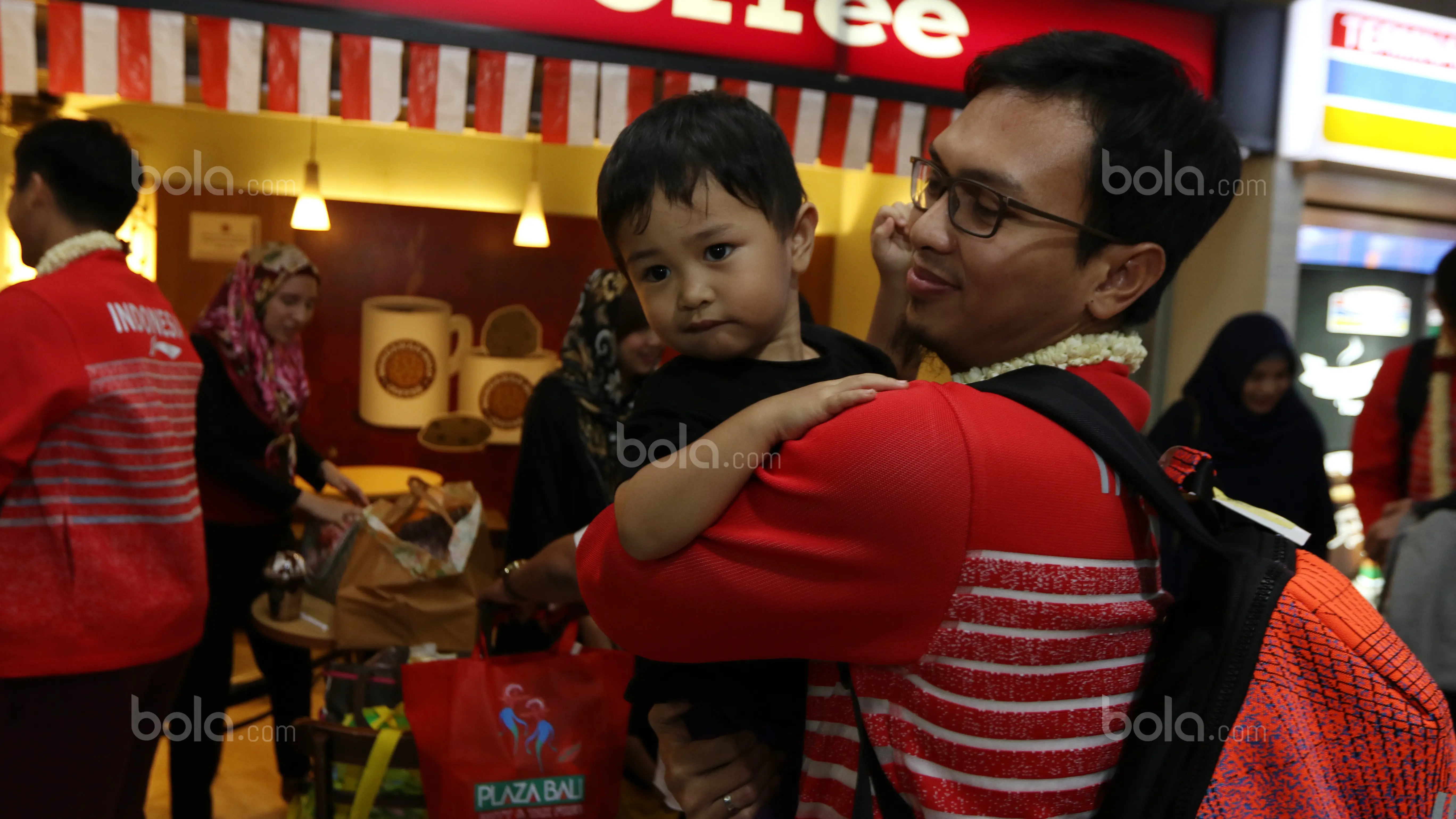 Mohammad Ahsan melepas rindu bersama anak saat tiba di Bandara Soekarno-Hatta, Cengkareng (29/8/2017). Aahsan dan Rian Agung hanya meraih medali perak pada kejuaraan dunia di Glasgow. (Bola.com/Nicklas Hanoatubun)