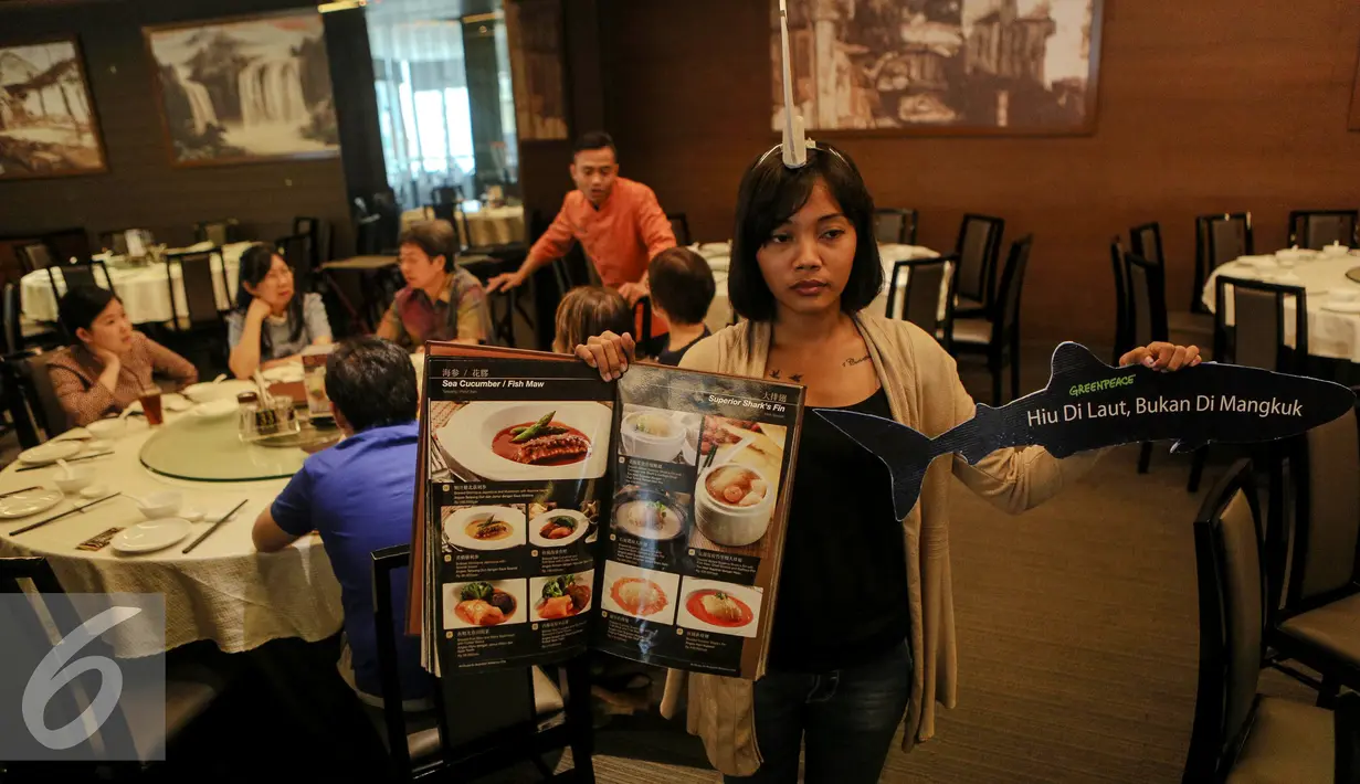 Aktivis Greenpeace Indonesia memperlihatkan menu makanan dan replika hiu saat menggelar kampanye di salah satu rumah makan , Jakarta, Minggu (12/7/2015). Aksi tersebut sebagai upaya menyelamatkan hiu dari kepunahan. (Liputan6.com/Faizal Fanani)