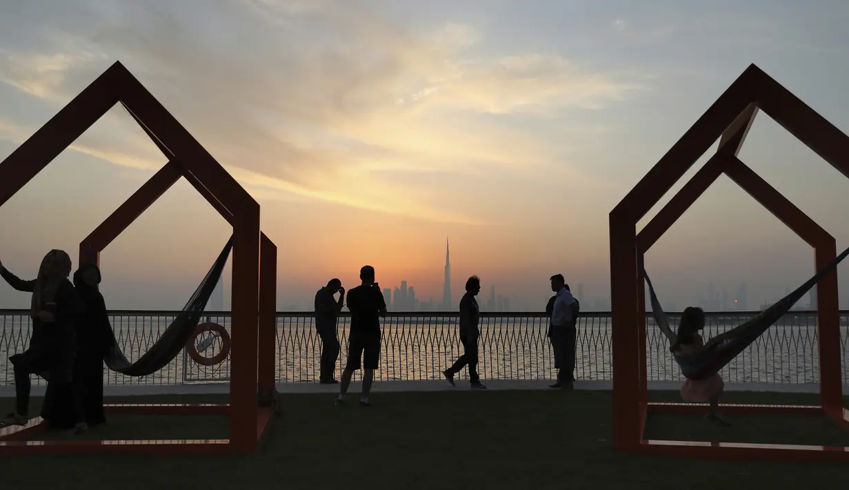 Orang-orang menikmati pemandangan cakrawala kota dengan latar gedung tertinggi di dunia Burj Khalifa, di Dubai, Uni Emirat Arab (18/10/2019). Burj Khalifa yang sebelumnya bernama Burj Dubai, adalah sebuah pencakar langit di Dubai, UEA yang diresmikan pada 4 Januari 2010. (AP Photo/Kamran Jebreili)