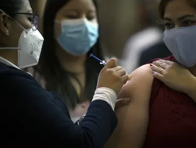 Seorang wanita muda menerima dosis pertama vaksin AstraZeneca di Mexico City, saat Meksiko menghadapi gelombang ketiga COVID-19, Selasa (10/8/2021). Hampir seperempat dari negara Meksiko berada dalam kondisi siaga merah karena infeksi Covid-19 naik ke level tertinggi. (ALFREDO ESTRELLA/AFP)