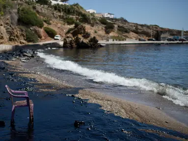 Kursi plastik di pinggir pantai yang berwarna hitam di Pulau Salamina, Yunani, Selasa (12/9). Warna hitam itu berasal dari tumpahan minyak kapal tanker Agia Zoni II yang tenggelam Minggu lalu saat akan berlabuh di pantai Salamina. (AP/Petros Giannakouris)