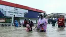 Seorang wanita bersama anaknya melintas di depan sebuah toko yang terendam banjir di Rantau Panjang, Selasa (3/1). Akibat hujan lebat yang turun terus menerus selama empat hari di Malaysia, 5.000 warga terpaksa dievakuasi. (AFP PHOTO/STR/Malaysia OUT)