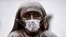 Masker terpasang pada wajah patung Bunda Teresa di Pristina, Kosovo, Kamis (19/12/2019). Pristina dan beberapa kota di Kosovo mengalami polusi udara tingkat tinggi. (Armend NIMANI/AFP)