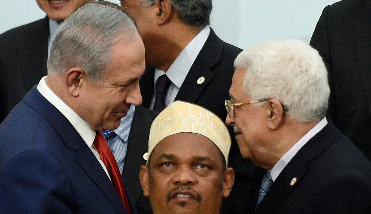 PM Israel Benjamin Netanyahu (kiri) berbincang dengan Presiden Palestina Mahmud Abbas dibelakang Presiden Komoro disela foto bersama pada KTT Perubahan Iklim, Conference of Parties (COP) 21 di Prancis, Senin (30/11). (AFP PHOTO/POOL/MARTIN BUREAU)