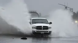 Sebuah kendaraan menerjang daerah banjir di Gregory Lane di Pleasant Hill, California, Minggu (24/10/2021). Badai kuat menerjang California Utara yang sempat mengalami kebakaran hutan, memicu tanah longsor dan banjir, juga membawa angin kencang. (Jose Carlos Fajardo/Bay Area News Group via AP)