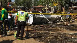 Penyelidik berdiri di dekat puing-puing Helikopter bell 429 yang membawa kepala polisi Filipina setelah jatuh di Kota San Pedro, selatan Manila, Kamis (5/3/2020). Saat helikopter lepas landas, debu beterbangan dan menciptakan awan debu tebal hingga mempengaruhi visibilitas di daerah tersebut.  (AFP)