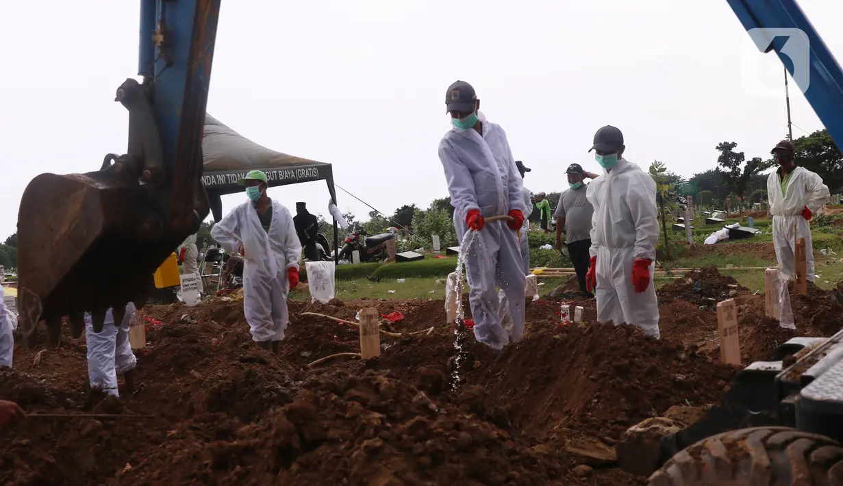Petugas dibantu alat berat saat melakukan pemakaman dengan prosedur Covid-19 di TPU Tegal Alur, Jakarta, Minggu (3/12/2021). Kini sejumlah jenazah Covid-19 dimakamkan di kawasan TPU Tegal Alur. (Liputan6.com/Angga Yuniar)