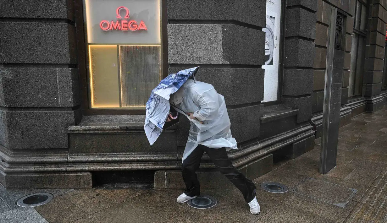 Warga menggunakan payung untuk berlindung dari hujan dan angin di kawasan The Bund, di Shanghai, Senin, 10 Agustus 2026. (AFP/ Hector Retamal)