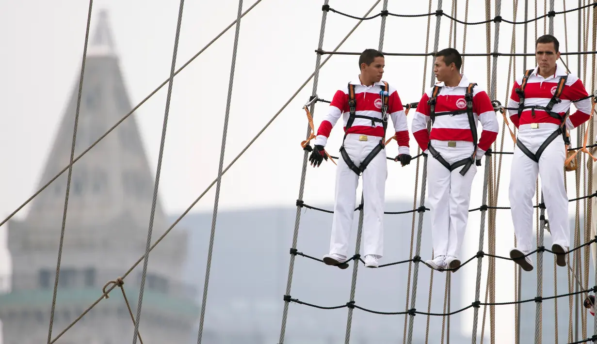 Tiga pelaut dari Angkatan Laut Peru berdiri di layar kapal saat mengikuti Parade Sail di Boston, AS (17/6). Dalam acara parade maritim ini diperkirakan 2 juta orang ikut berpartisipasi. (AP Photo / Michael Dwyer)