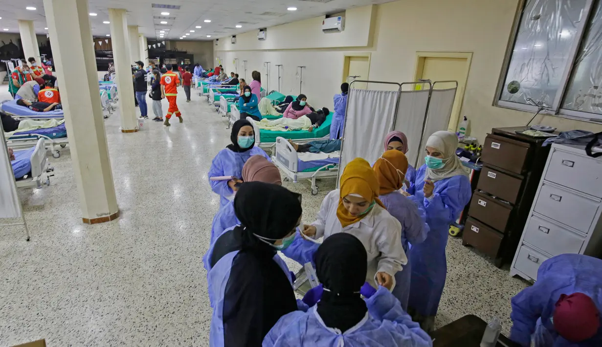 Staf medis berbicara di bangsal untuk pasien yang dirawat dalam wabah kolera Vibrio di aula masjid yang diubah menjadi rumah sakit lapangan di Kota Bebnine, Distrik Akkar, Lebanon Utara, Rabu (26/10/2022). Pada 13 Oktober, total 18 kasus telah dikonfirmasi, termasuk dua kemungkinan kematian. (AFP/Ibrahim Chalhoub)