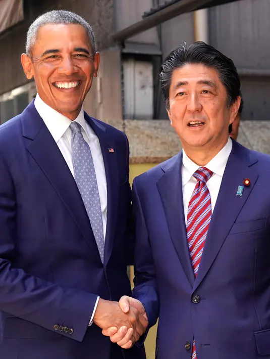 Presiden AS ke-44 Barack Obama bersalaman dengan PM Jepang, Shinzo Abe saat tiba di restoran sushi di kawasan Ginza, Tokyo, Jepang, (25/3). Ini merupakan kunjungan Obama ke Jepang setelah tidak lagi menjabat Presiden AS. (AP Photo/Shizuo Kambayashi, Pool)