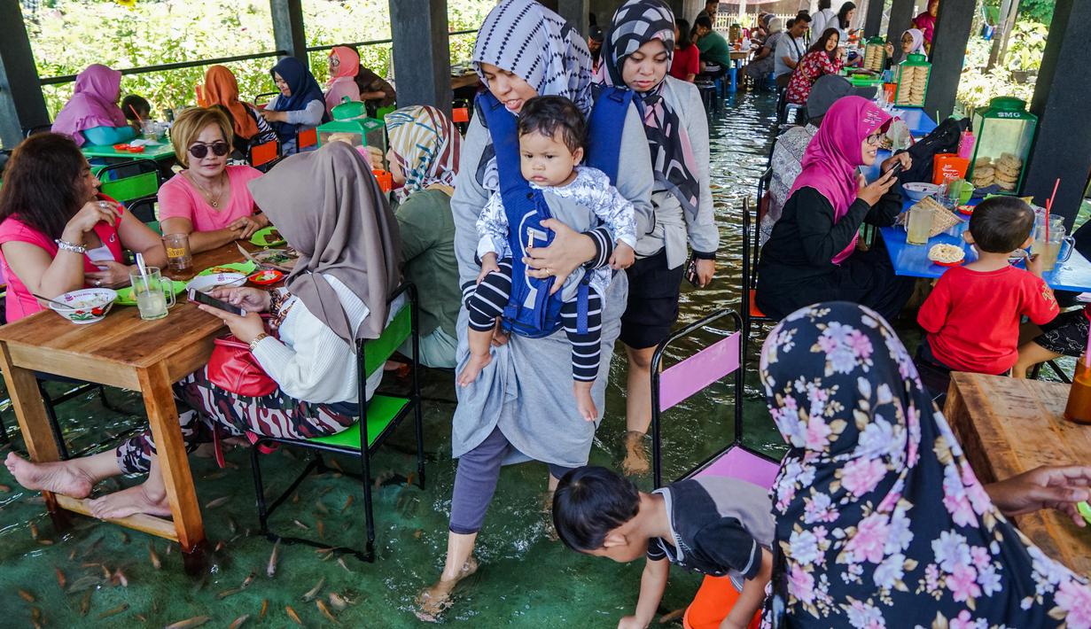 Suasana restoran kolam ikan di desa Wedomartani di Yogyakarta (15/11/2019). Pengunjung bisa menikmati makanan sambil merendam kakinya di kolam ikan kecil. (AFP Photo/Oka Hamied)