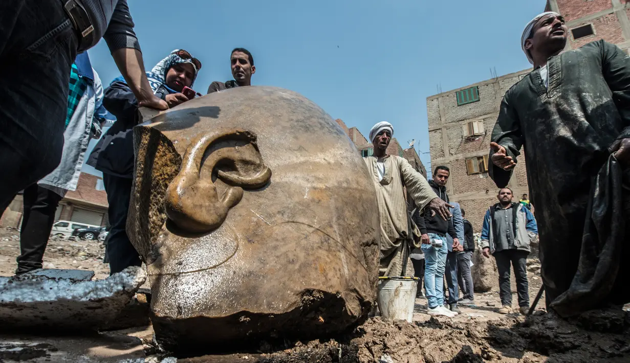 Warga melihat dekat pecahan patung yang ditemukan oleh tim arkeolog Jerman-Mesir di distrik Mattarya, Kairo, Kamis (9/3). Diduga pecahan patung yang digali di sekitar Kuil Ramses II tersebut berasal dari dinasti XIX (1295-1185 SM)