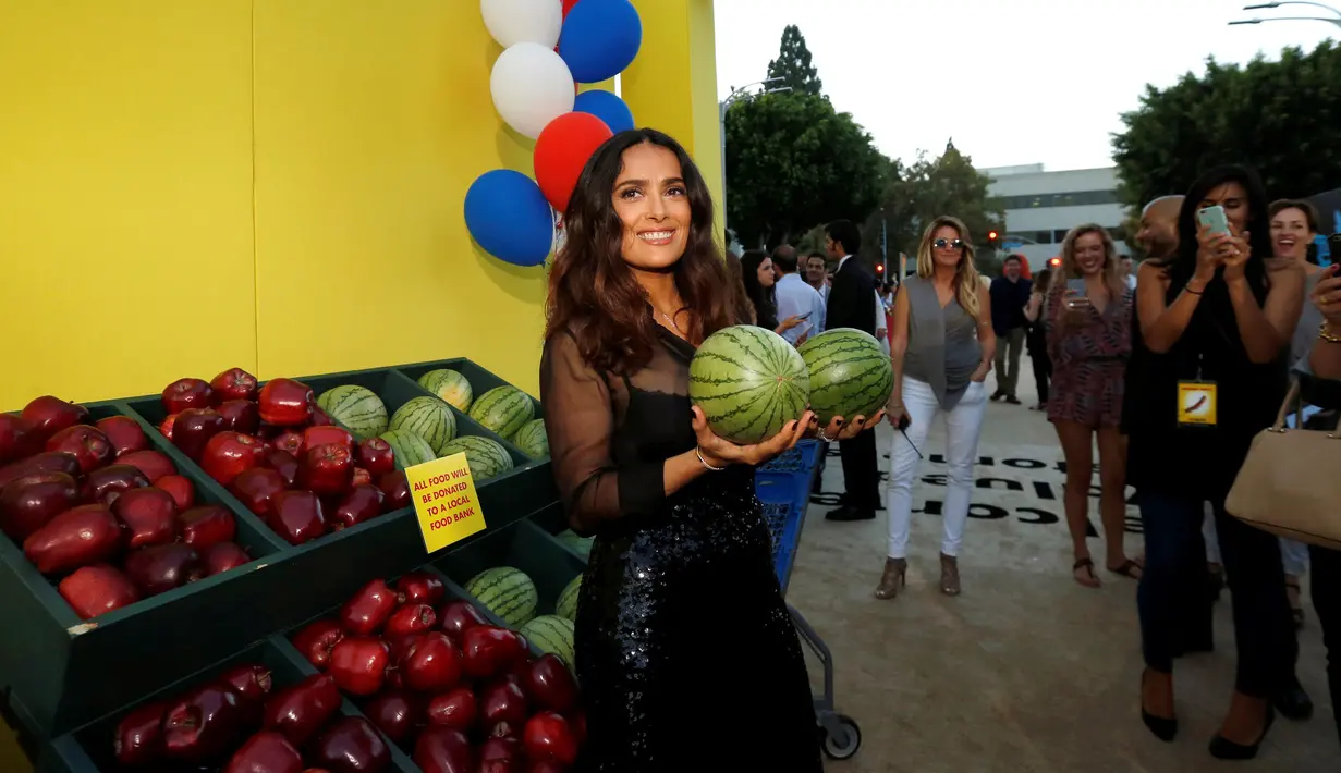 Artis Salma Hayek berpose dengan memegang dua buah semangka saat pemutaran perdana film "Sausage Party" di Los Angeles, California AS (9/8). Salma Hayek tampil dengan gaun hitam dengan balutan atasannya yang transparan. (REUTERS/Mario Anzuoni)