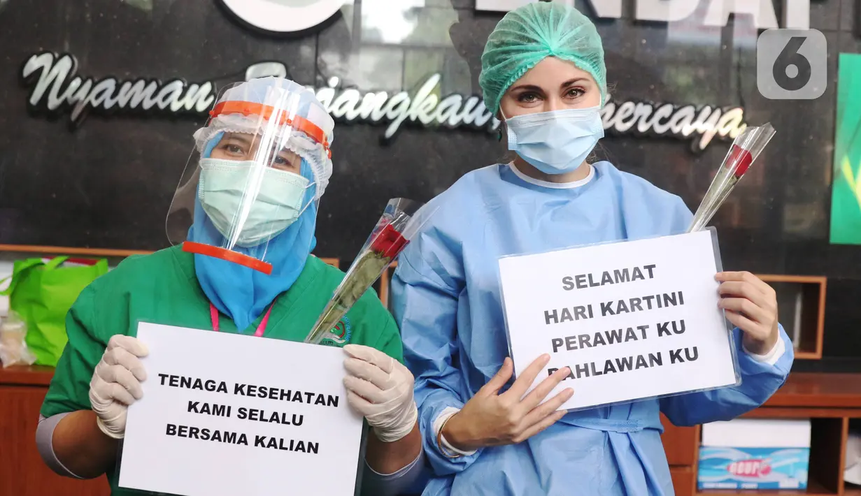 Tenaga medis menunjukkan bunga mawar dan ucapan selamat Hari Kartini di RSUD Kota Tangerang, Selasa (21/4/2020). Komunitas Taman Potret Tangerang menyambut Hari Kartini dengan mendatangi RSUD Kota Tangerang untuk memberikan bunga dan APD kepada tenaga medis perempuan. (Liputan6.com/Angga Yuniar)